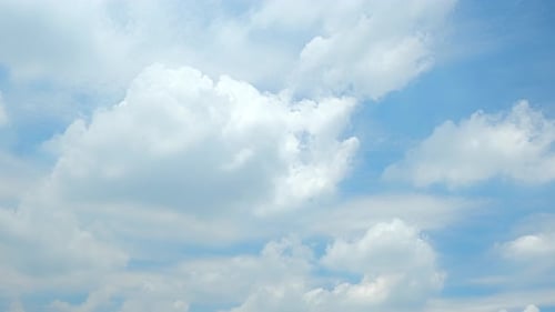 Fluffy White Clouds Float in Blue Sky