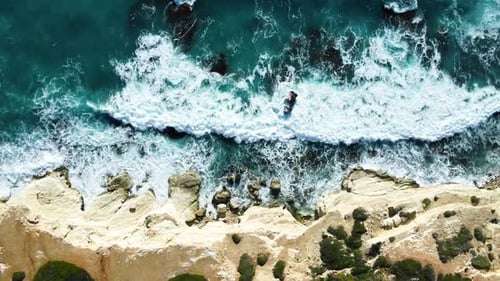 Flying Over Rocky Coastline Alongside Cliffside with Blue Mediterranean Sea Ocean Water Towards the