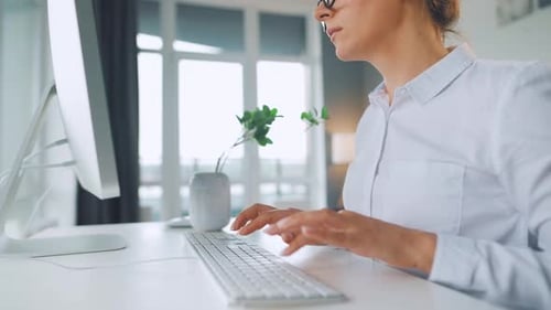 Woman Typing on Computer Keyboard at Desk