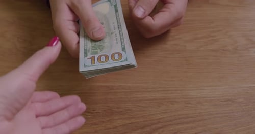 Hands Counting Stack of Money on Table