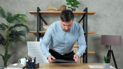 Businessman comes to office workplace sit on chair at desk start using laptop