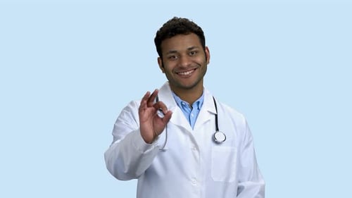 Fröhlicher Doktor mit Stethoskop zeigt Ok-Zeichen
