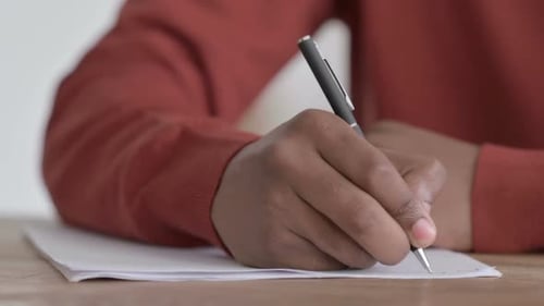 Hände Nahaufnahme eines afrikanischen Mannes, der auf Papier schreibt