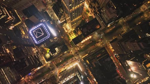 Cars Driving on Street Between High Rise Buildings in Night City