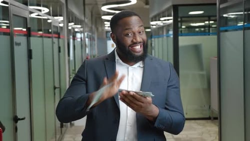 Glücklicher afrikanischer Geschäftsmann verteilt die Dollars im Amt und feiert erfolgreichen Deal