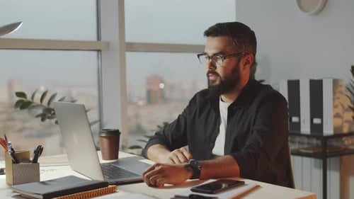 Bearded Businessman Video Calling on Laptop in Office