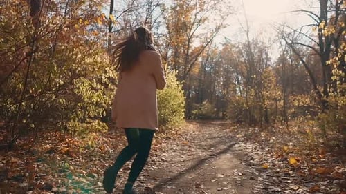Woman Twirling Down Leafy Path in Autumn Forest