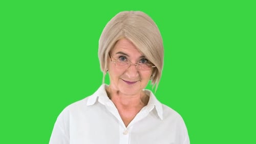Grandmother in Glasses and with Gray Hair Happy and Smiling Looking To Camera on a Green Screen
