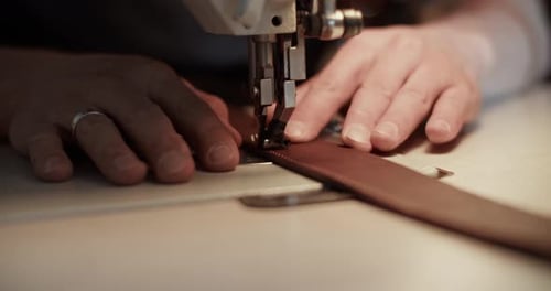 Sewing Machine Stitches Brown Fabric in Workplace
