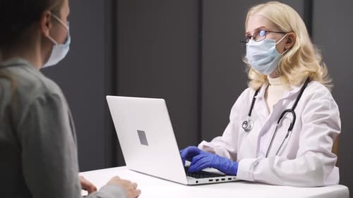 Doctor Typing at Desk During Appointment