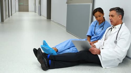 Doctor and Nurse Using Laptop in Hospital Hallway