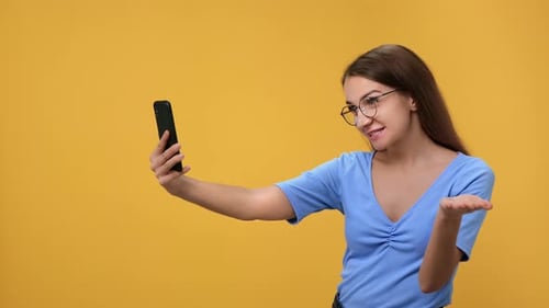 Happy Modern Young Woman Talking Online Video Call Use Smartphone Isolated on Orange Studio