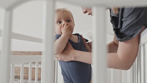 Loving Parent Holds Cute Baby in White Crib