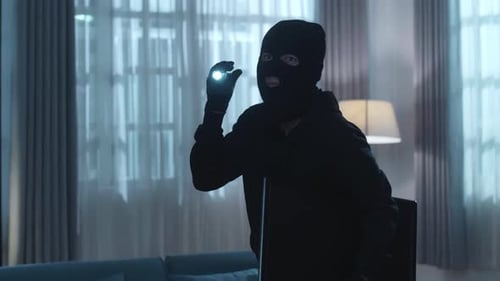 Masked Person with Flashlight and Computer Indoors
