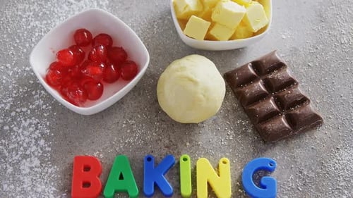 Baking Ingredients with Colorful Lettering on Floury Countertop