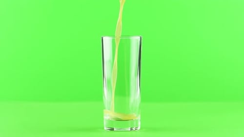 Juice Pouring Into Glass Isolated on Light Green Background
