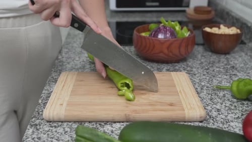 Girl Cutting Green Chili Pepper With Knife On A Cutting Board