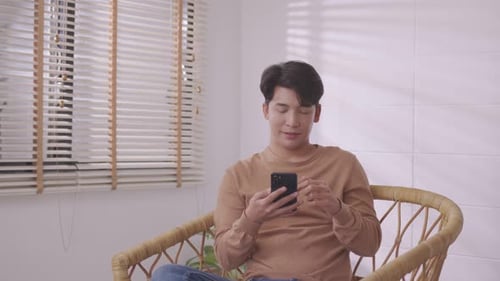 Young Man Using Smartphone in a Chair