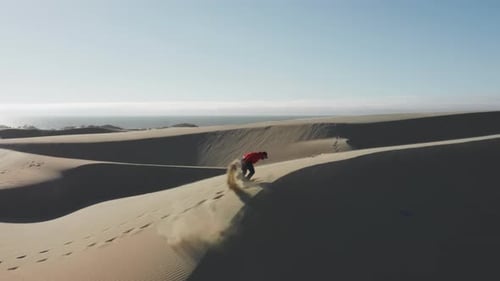El hombre corre enérgicamente por las dunas creando nubes doradas de arena al atardecer