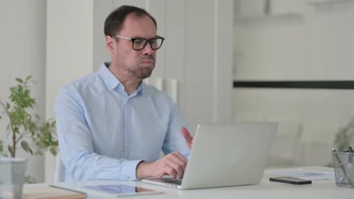 Middle Aged Man Coughing While Using Laptop in Office