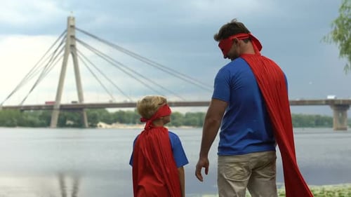Father and Child in Superhero Costumes by River