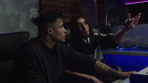 Multiethnic Sound Producer and Technician Working at Mixing Console Creating Track in Music Studio
