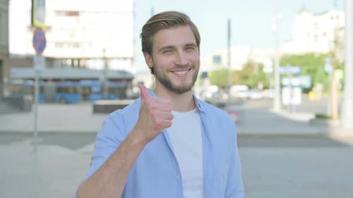 Young Man Giving Thumbs Up Outdoors
