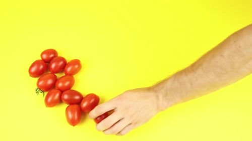 Hand Rests Tomatoes on Yellow Table