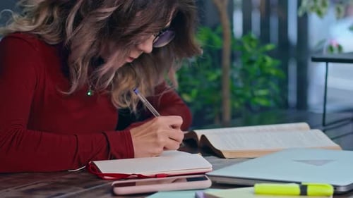 Eine junge traurige Studentin, überwältigt von Hausaufgaben, sitzt mit einem Laptop in einem Café