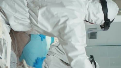 Dentists in Protective Gear Perform Dental Procedure