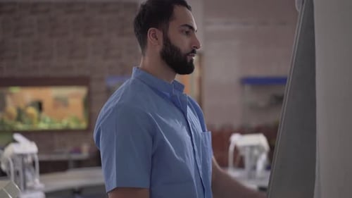 Side View of Confident Handsome Middle Eastern Man Writing on Board in Dentistry Audience