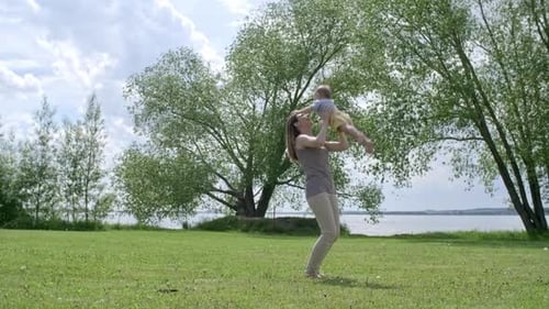 Happy Woman Lifting Baby in Air