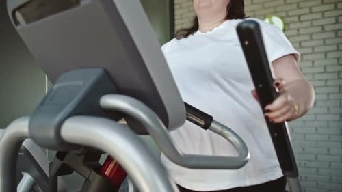 Chubby Woman Using Elliptical Trainer