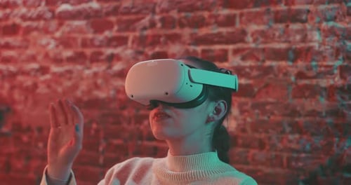Close up shot of young woman in vr goggles experiencing the metaverse with her hands up