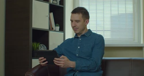 Young Adult Using Tablet on Couch at Home