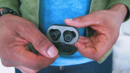 Person Holds Open Case with Wireless Ear Buds