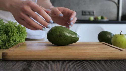 Woman Halves Fresh Avocado in Kitchen
