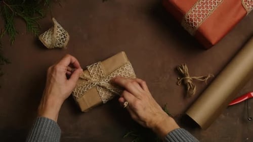 Hands Tying Ribbon on Christmas Gift at Home