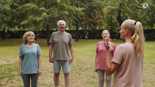 Female Fitness Coach Speaking to Senior People in Park