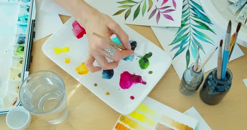 Woman Mixing Watercolor Paints on a Palette