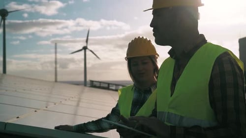 People working for alternative energy with wind turbine and solar panel