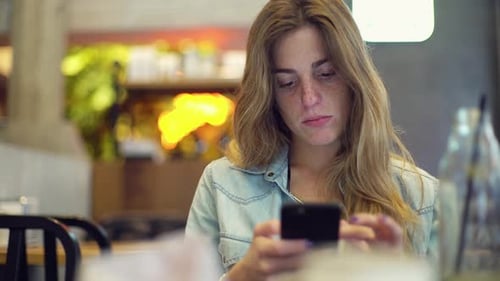 Woman Using Smartphone and Drinking in Cafe