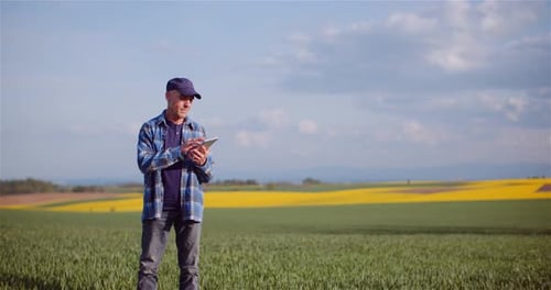 Farmer Examining Agricultural Field While Working on Digital Tablet Computer at Farm