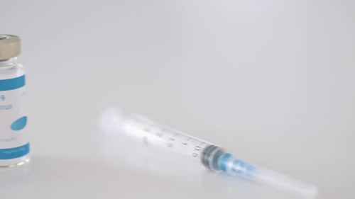 COVID-19 Vaccine Vials and Syringe on White