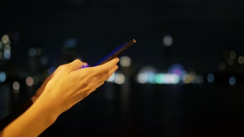 Woman Using Phone at Night With City Background