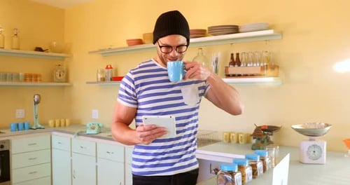 Man Using Tablet While Drinking in Kitchen