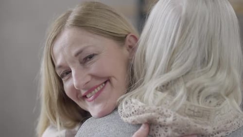 Adult Woman Lovingly Hugs Gray-haired Senior Woman