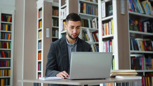Young Adult Using Laptop in Library Setting