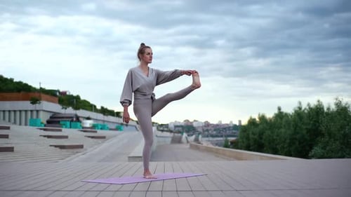 Woman Practices Tree Pose Yoga in Urban Setting
