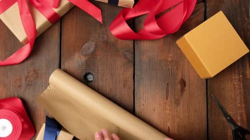 Hands Wrapping Gift on Wooden Table